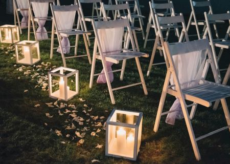 Colorful folding chairs set up outdoors at dusk, with string lights and a sign reading &ldquo;Live Music.&rdquo;